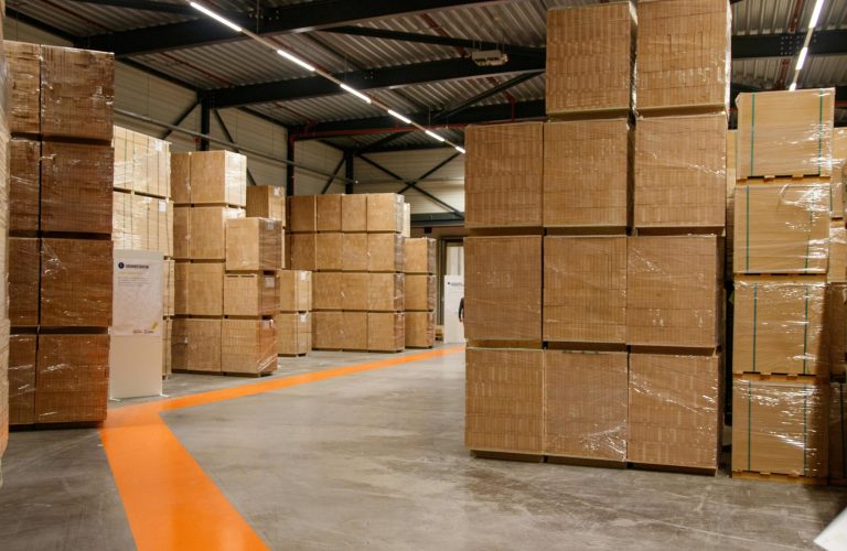 A spacious industrial warehouse filled with stacked cardboard boxes for storage and shipping.