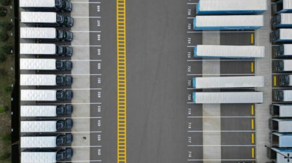 Top-down view of lined-up trucks at a logistics parking lot, showing organized transportation hub.