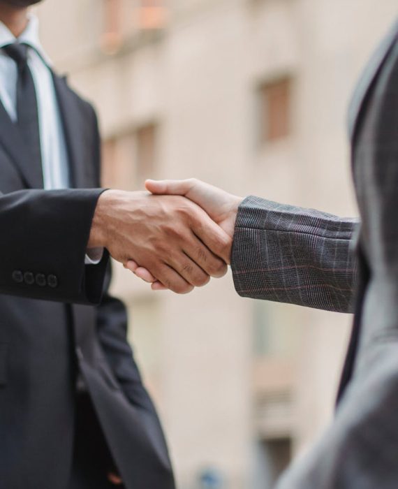 Business professionals greeting each other with a handshake outdoors, symbolizing partnership.